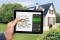 Tablet with modernisation calculator; in the background: Detached houses